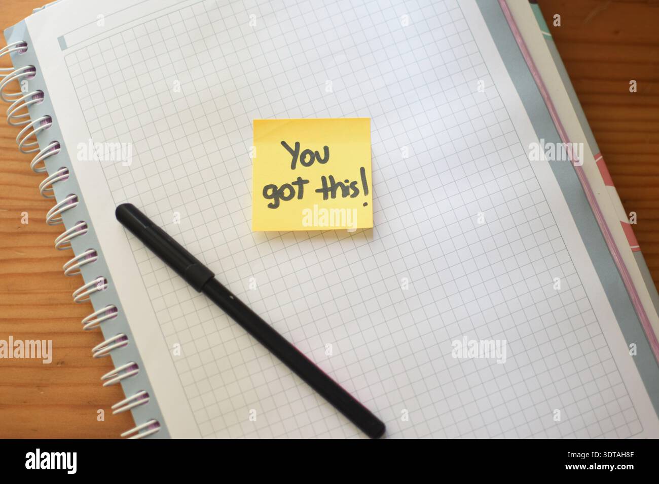Image haute résolution vue de dessus d'une note autocollante jaune avec la phrase manuscrite "You Got This" placée sur un bloc-notes quadrillé avec un crayon noir Banque D'Images