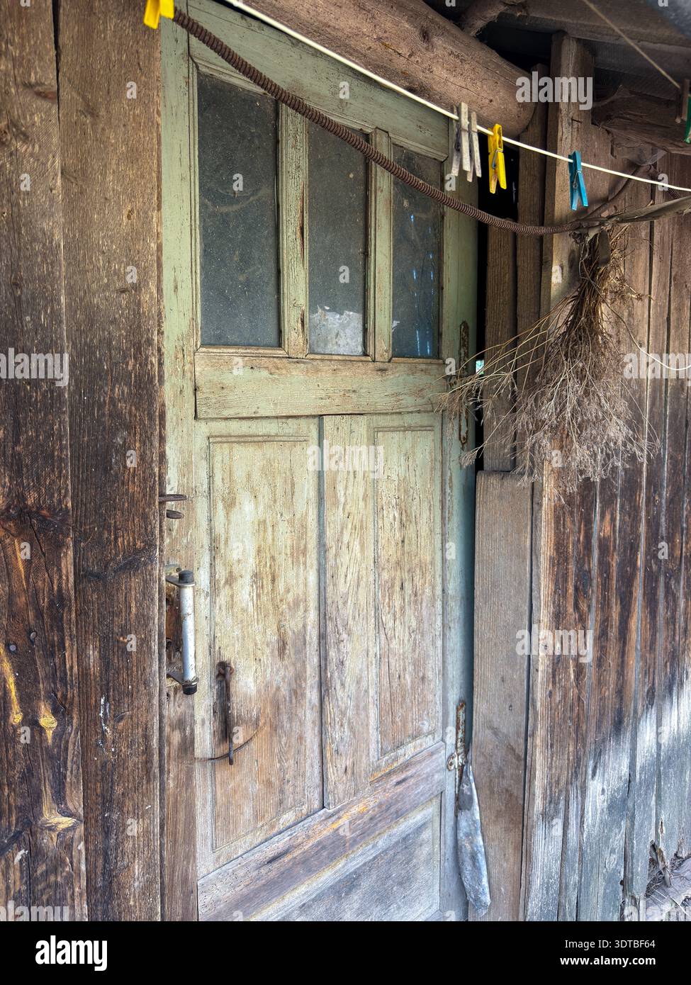 Façade rustique en bois montrant une vieille porte et une ligne de séchage Banque D'Images