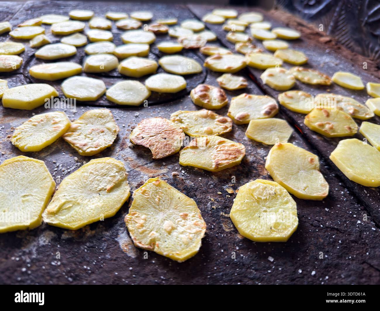 Tranches de pommes de terre séchant sur la surface rustique du poêle Banque D'Images