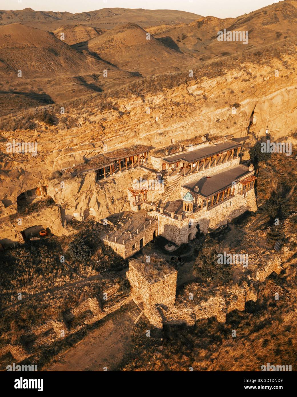 Vue aérienne d'un moine orthodoxe marchant dans un monastère caverne isolé creusé dans des falaises, symbolisant la dévotion spirituelle, l'isolement et le Li ascétique Banque D'Images