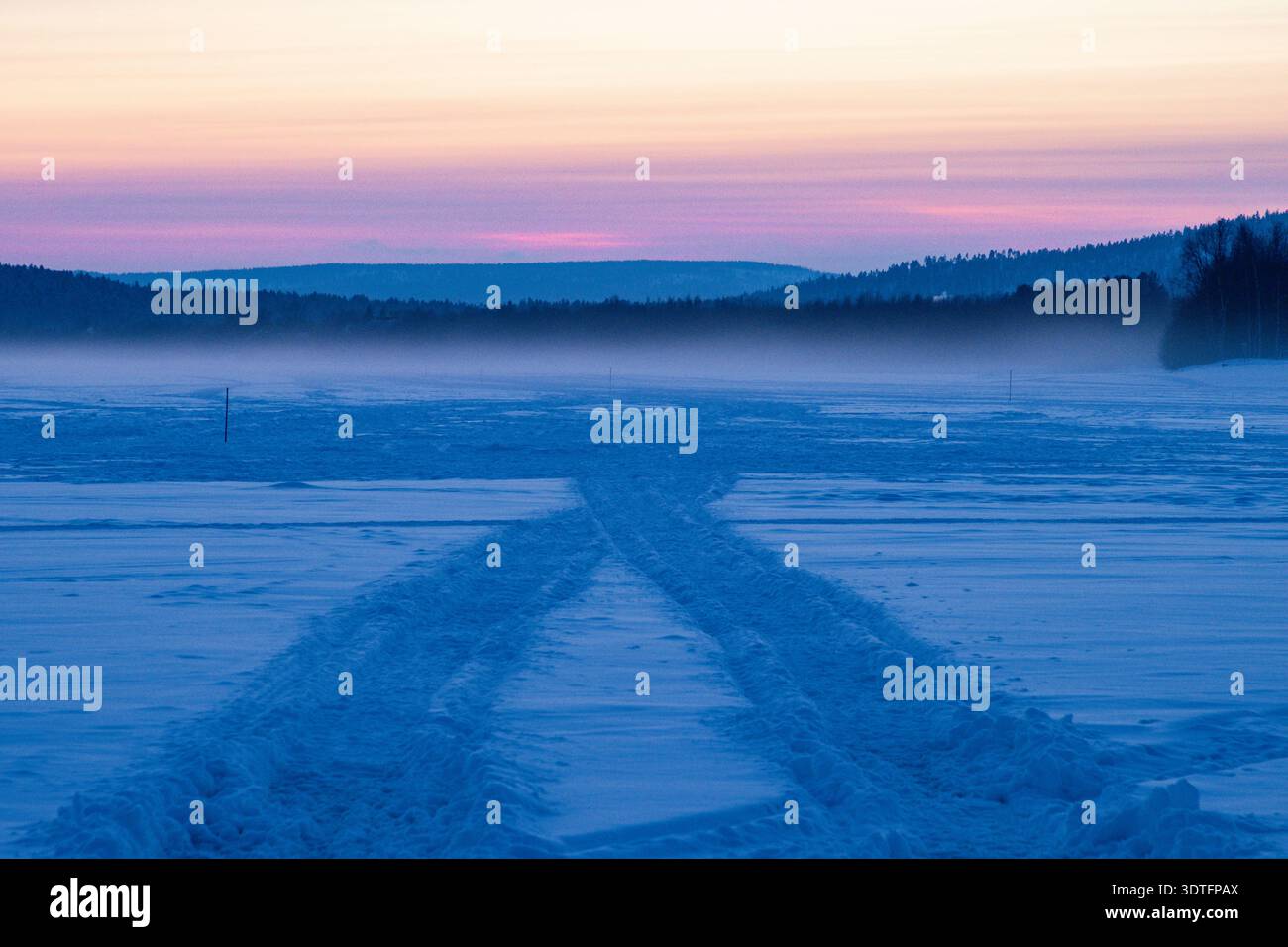 Coucher de soleil sur le lac Inari gelé avec des arbres couverts de neige en Laponie, Finlande près d'Ivalo Banque D'Images