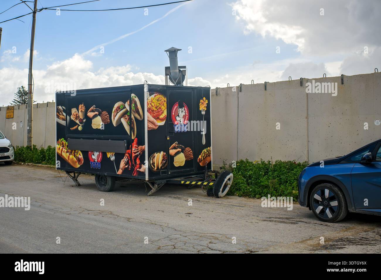 Gzira, Malte - 17 février 2026 : vue d'une remorque mobile noire de Street food avec un tuyau d'échappement pour la cuisine et les images de restauration rapide garée dans une rue. Banque D'Images