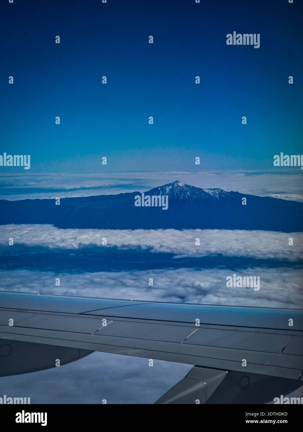 Vue du volcan du Teide s'élevant au-dessus d'une couverture de nuages comme vu d'une fenêtre d'avion. Sommet enneigé et paysage volcanique de Tenerife cr Banque D'Images