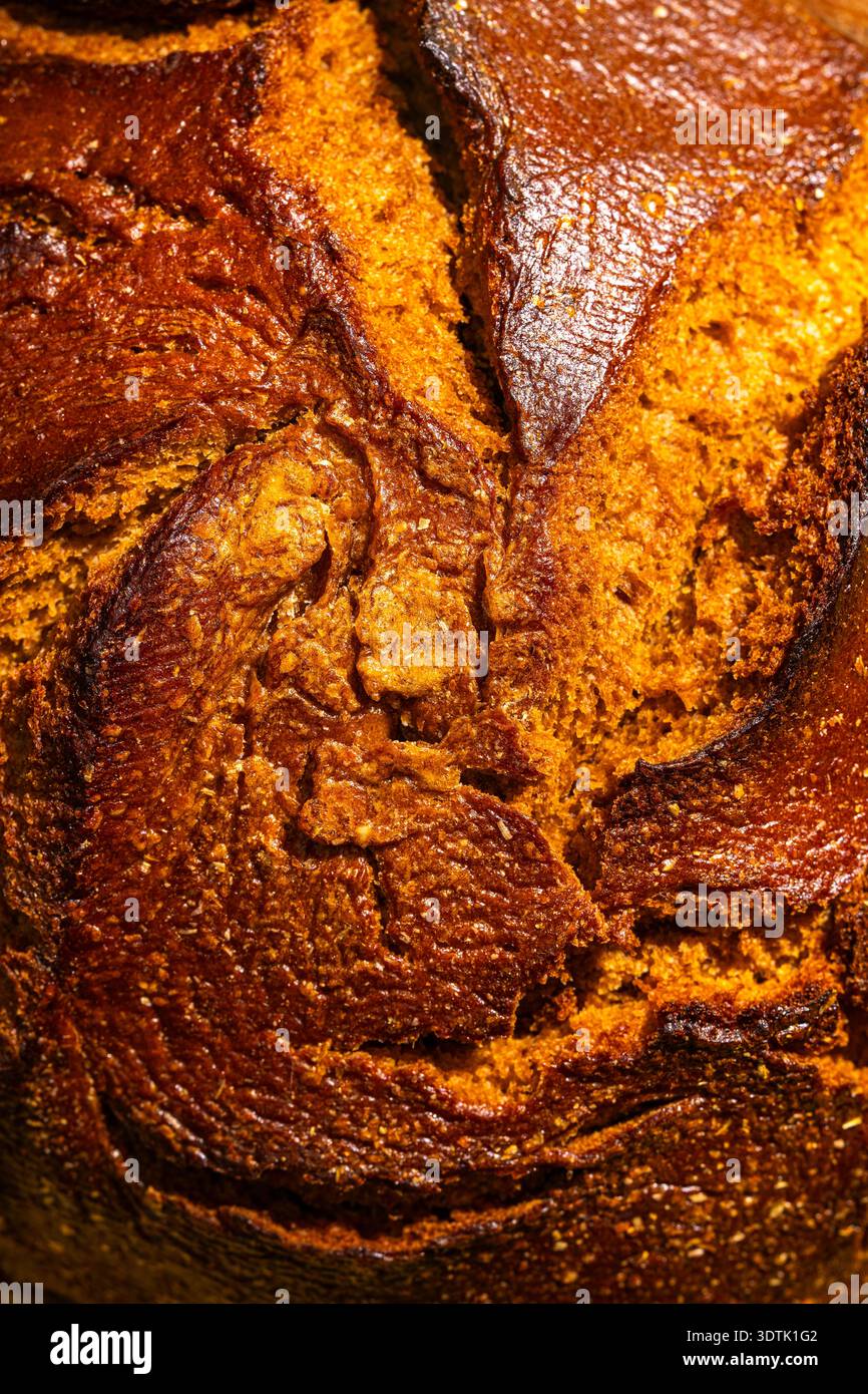 Image en gros plan capturant la texture complexe d'un pain artisanal fraîchement cuit, mettant en valeur sa riche croûte brun doré et ses miettes invitantes Banque D'Images