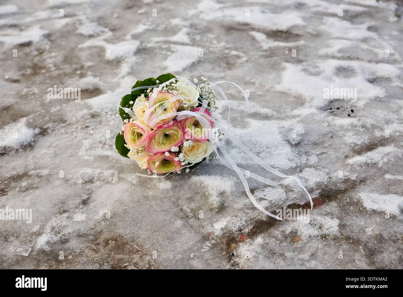 Un bouquet de mariage vibrant, avec un mélange de ranoncule rose et crème, roses blanches, et délicat souffle de bébé blanc, repose sur une surface texturée de Banque D'Images