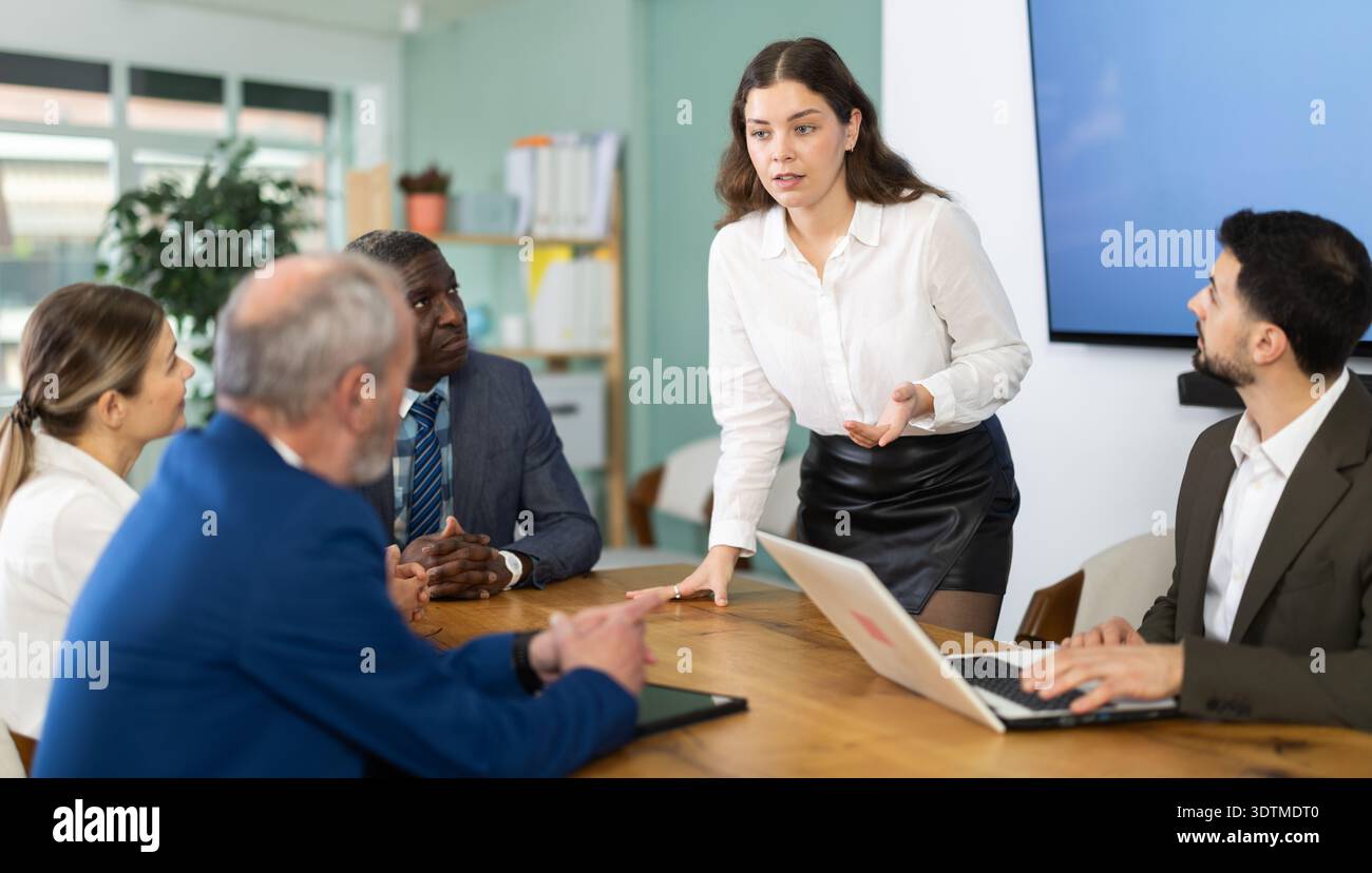 Femme parlant à des collègues qui sont assis à une table Banque D'Images