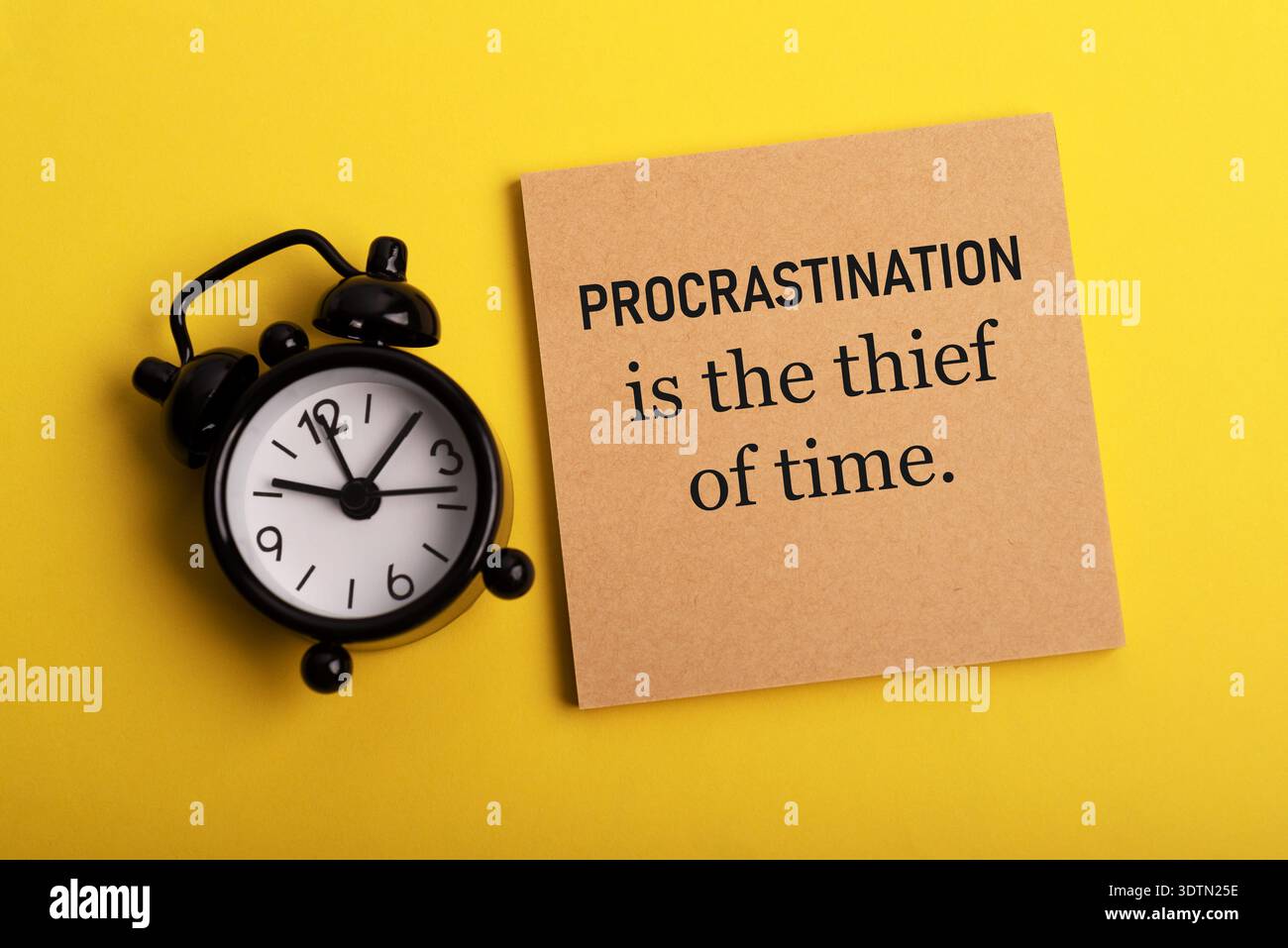 Réveil et note de papier avec des citations inspirantes - Procrastination est le voleur du temps Banque D'Images