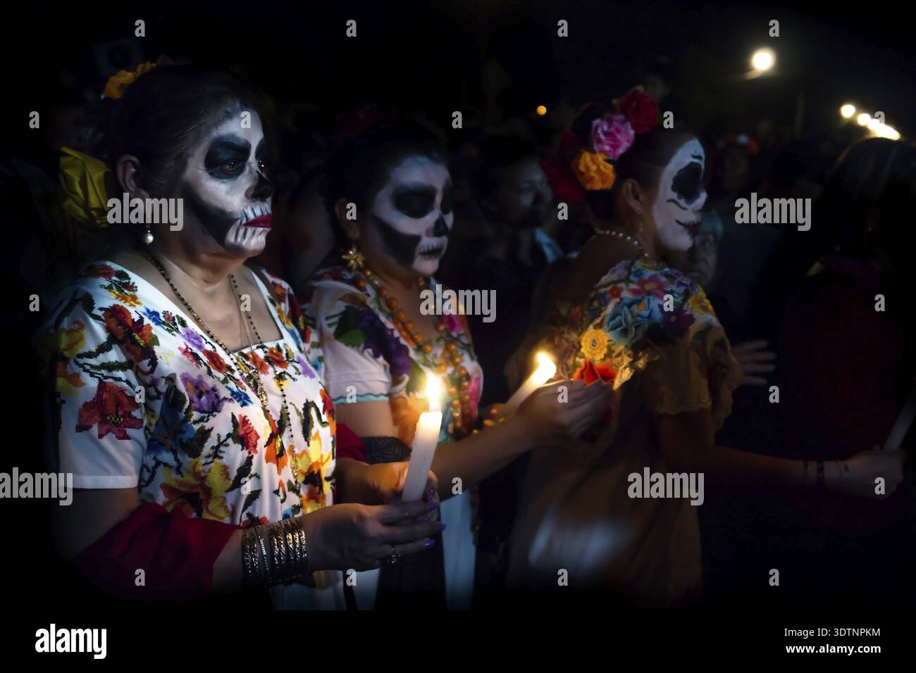 Merida, Mexique, Général Cementerio - 31 octobre 2018 : Trois femme sur mesure habillé en Catrinas avec tête de make-up des problèmes avec le pari de bougies Banque D'Images