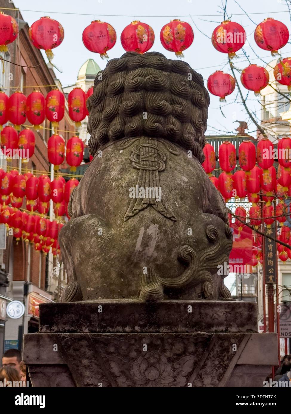 Londres, Royaume-Uni. 22 février 2026. Statue de lion gardien en pierre traditionnelle chinoise, ornée de rubans rouges festifs et de décorations pour le nouvel an lunaire. Située à l'entrée du quartier chinois de Londres, la statue sert de repère culturel pendant l'année des célébrations du cheval de feu, symbolisant la protection et la prospérité de la communauté locale et des visiteurs. Crédit : Glosszoom/Alamy Live News Banque D'Images