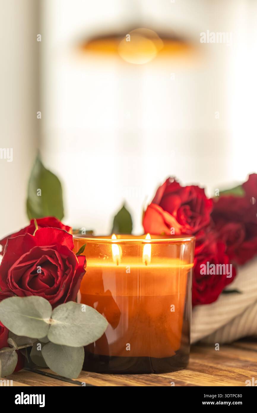 Flammes chaudes de bougie parmi les roses en bokeh doux. Éclat romantique. Banque D'Images