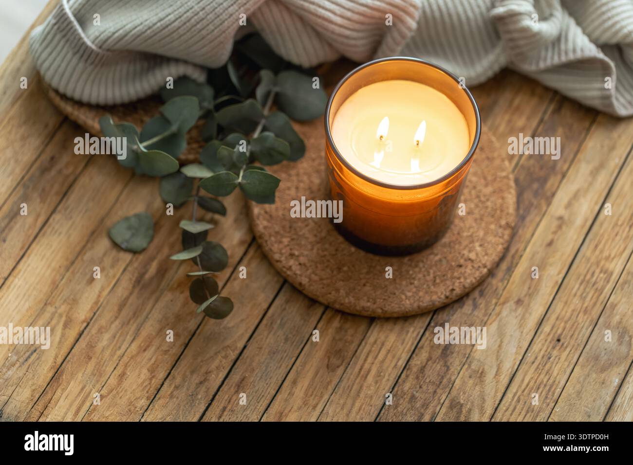 Bougie chaude lueur dans le verre ambré sur la table en bois. Rituel confortable. Banque D'Images