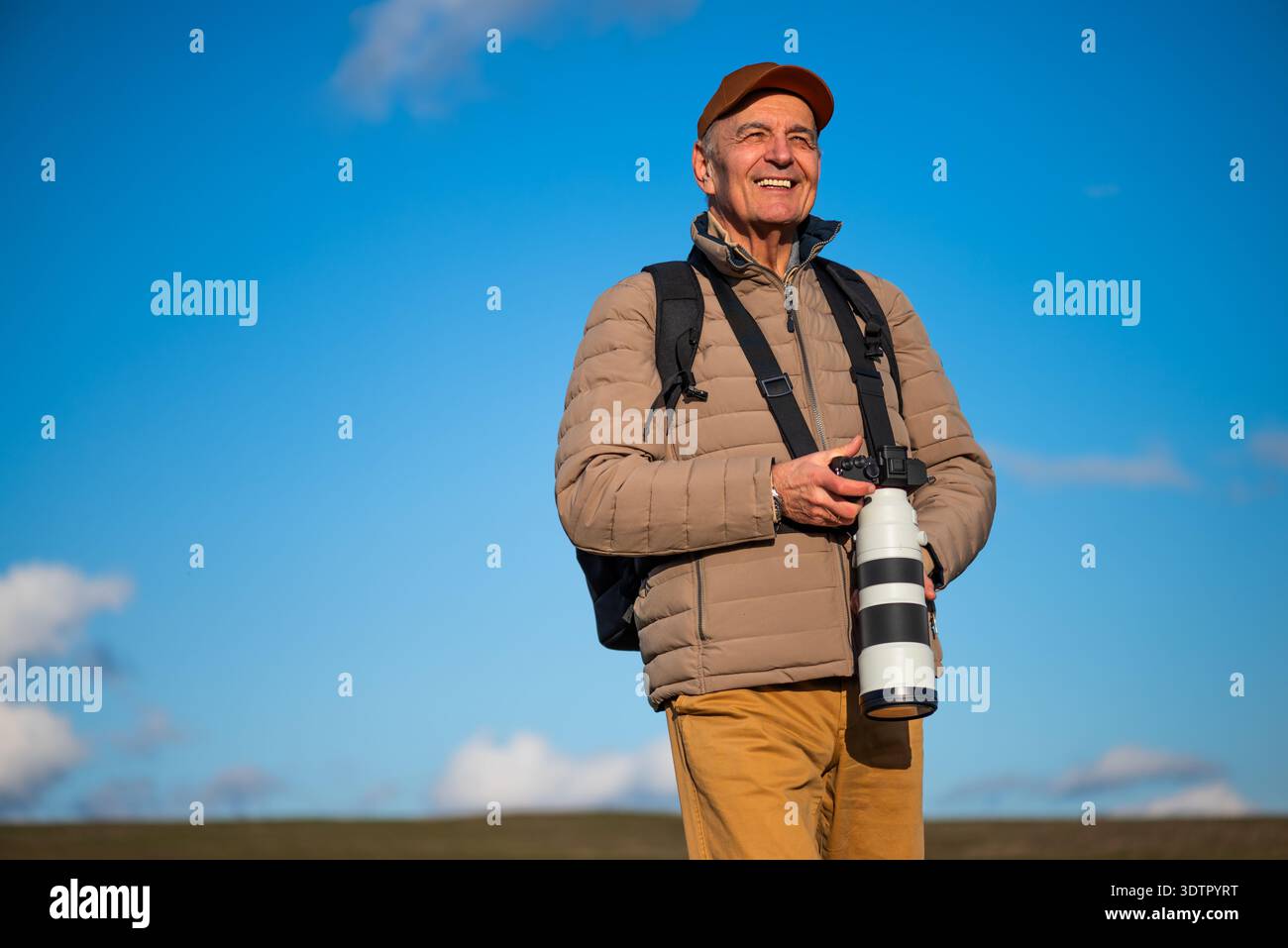 Un homme âgé avec un appareil photo numérique et un téléobjectif explore la nature, en se concentrant sur l'obtention de la photo parfaite contre. Banque D'Images