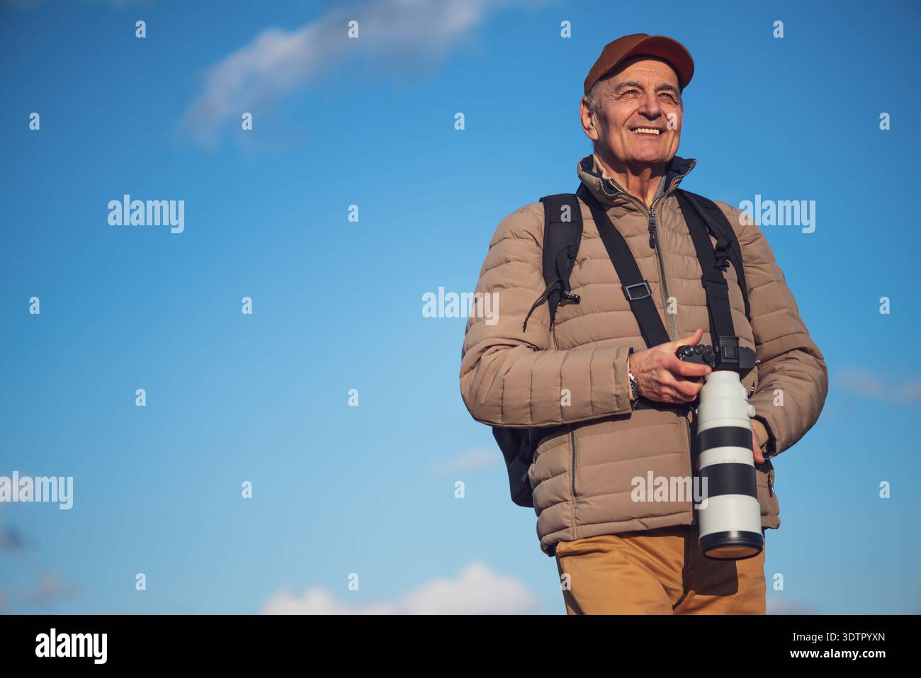 Portrait d'homme senior, passionné de photographie qui se tient debout à l'extérieur, profitant d'une journée claire dans la nature. Banque D'Images