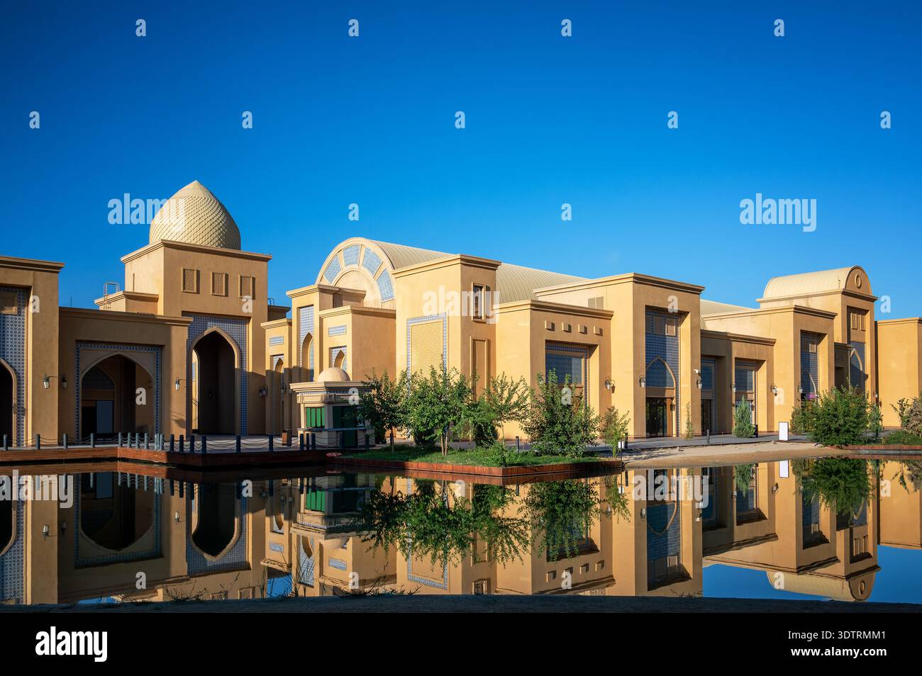 Le complexe Karavan Saray se reflète dans l'eau calme au Turkestan, Kazakhstan, créant une vue symétrique de la conception architecturale moderne. Banque D'Images