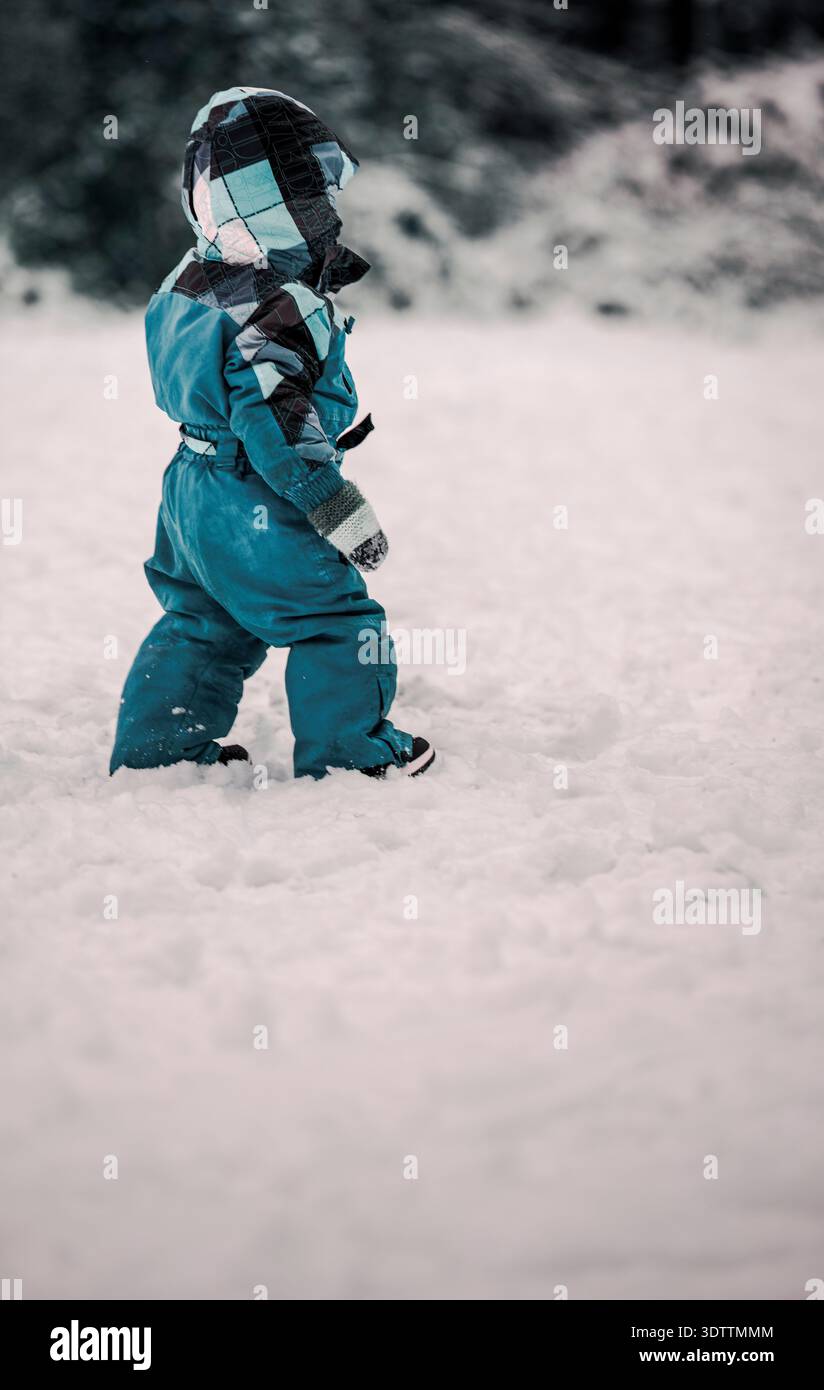 Enfant enveloppé dans des vêtements chauds marchant dans la neige Banque D'Images