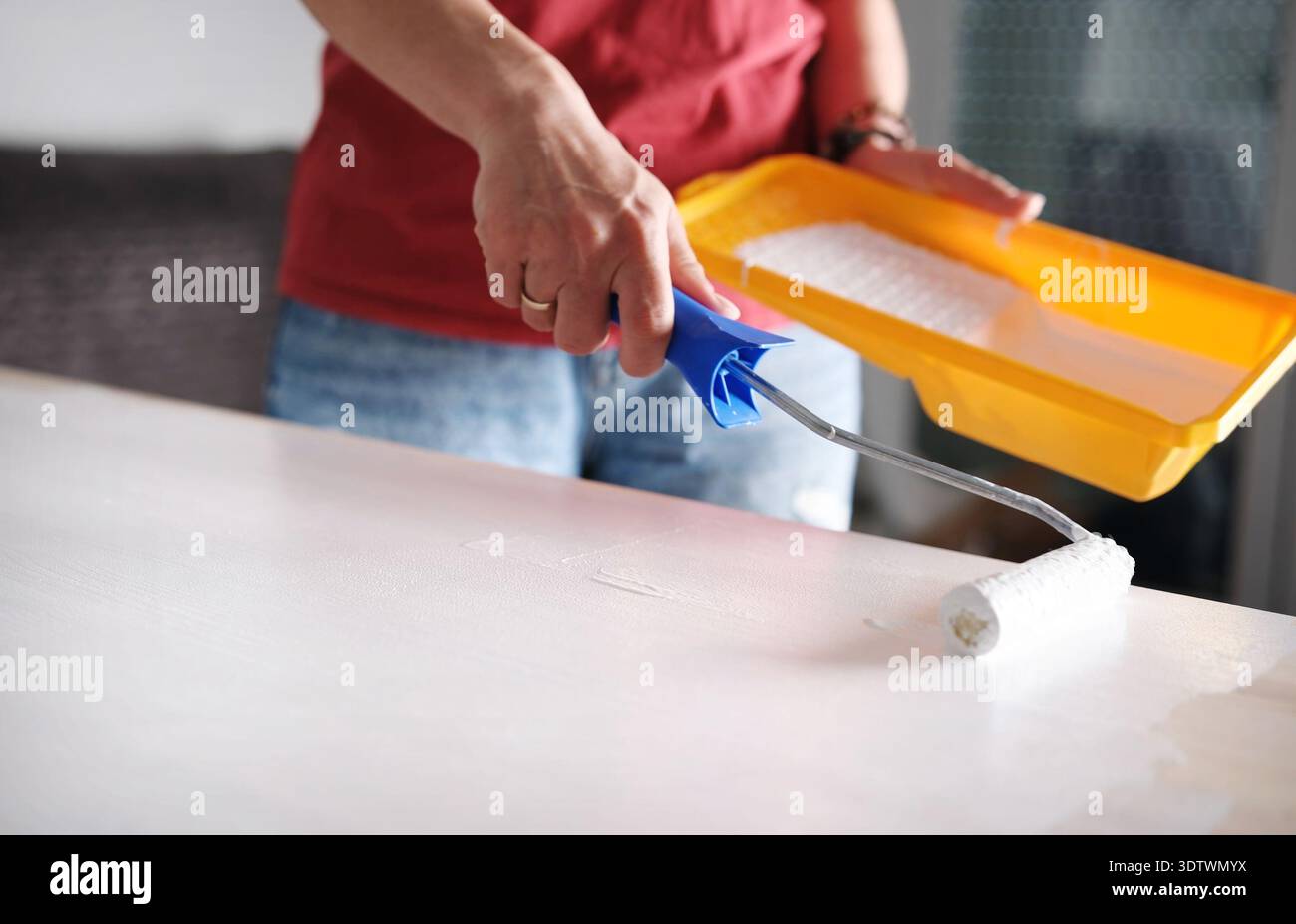 Fille utilise Un rouleau pour peindre Une planche en bois blanc dans Une vue rapprochée Banque D'Images