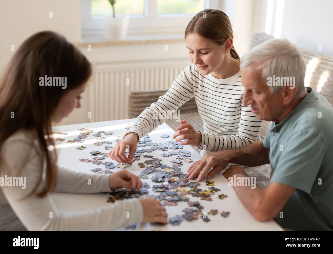Grand-père et petites-filles travaillent sur Un Puzzle ensemble, différentes générations d'Une famille passant du temps ensemble Banque D'Images