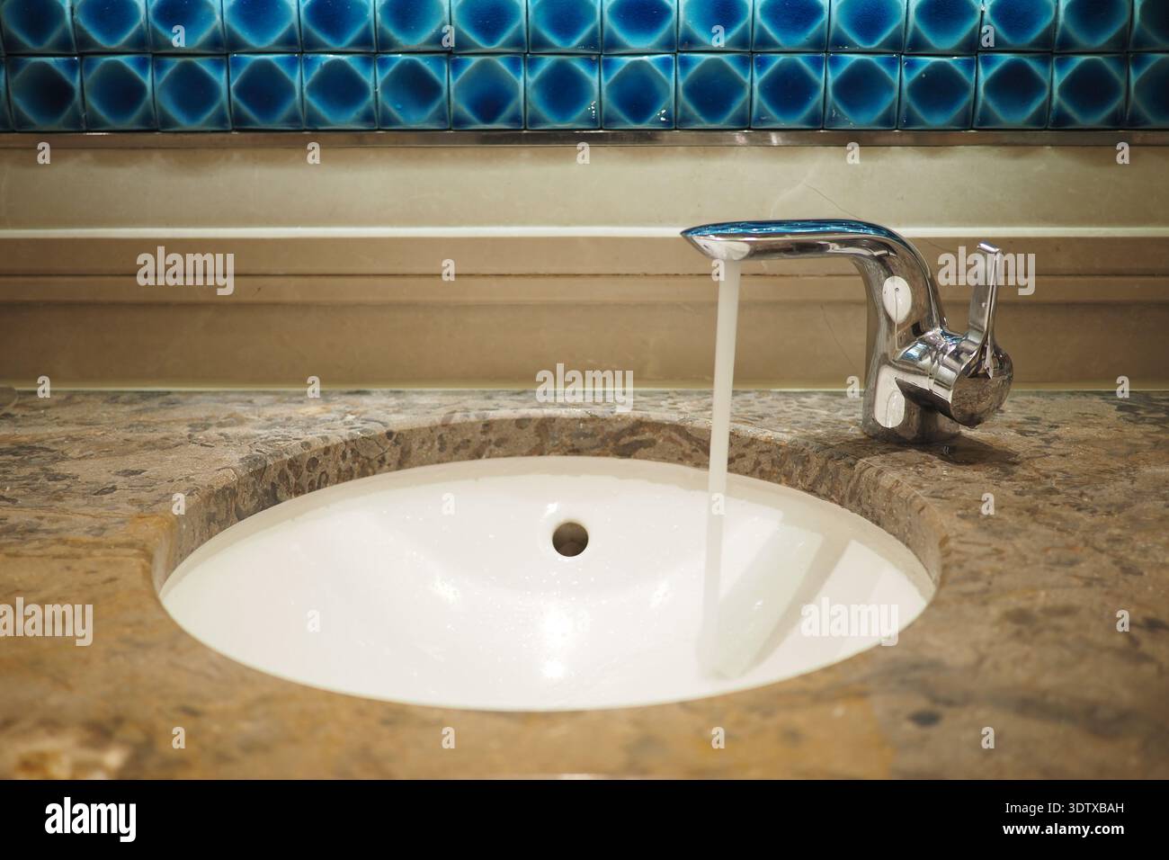 L'eau s'écoule d'un robinet dans un évier de salle de bains Banque D'Images