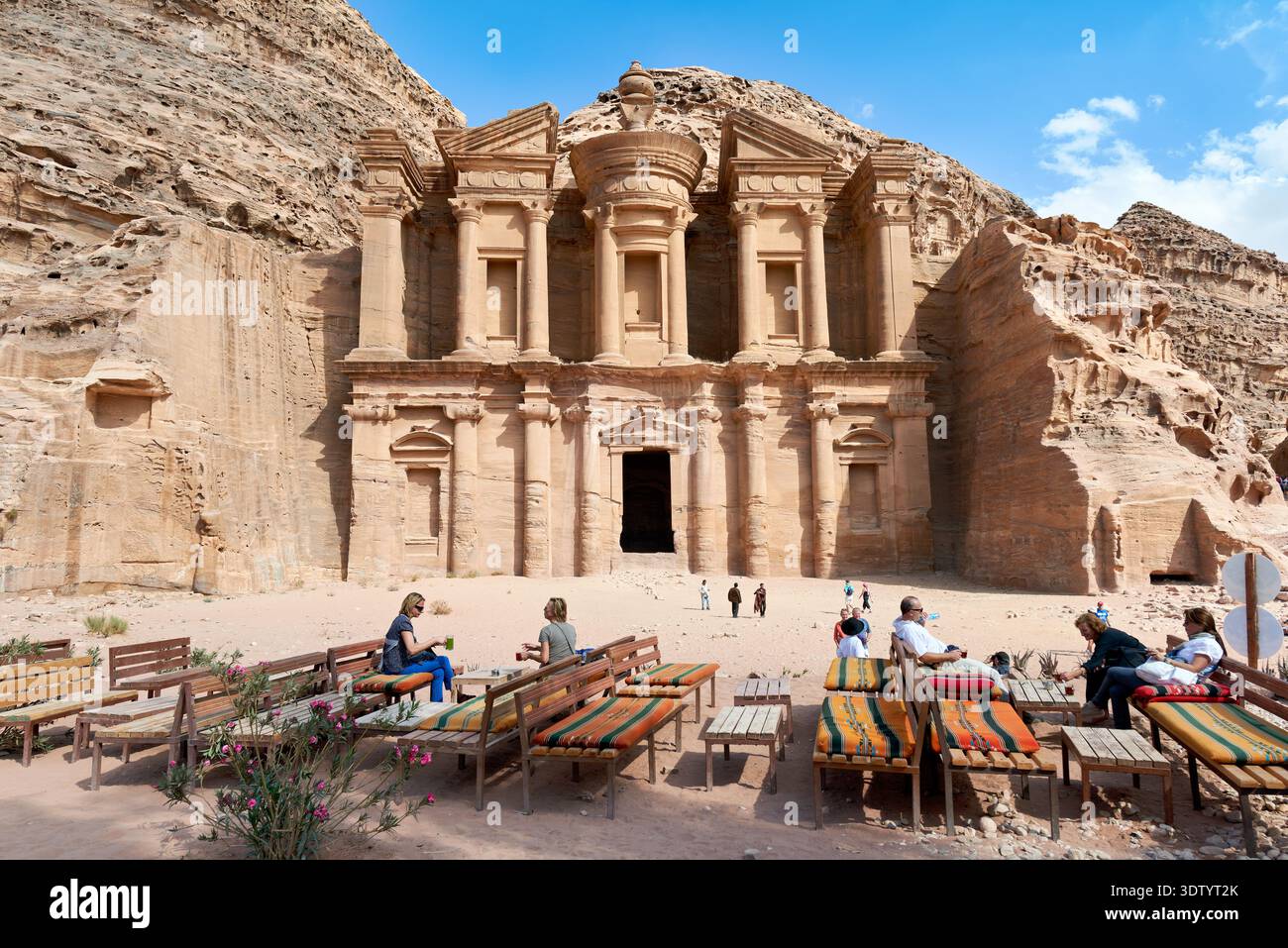 Les visiteurs se détendent et prennent le thé près du monastère de Pétra. La scène montre l'ancien bâtiment taillé dans la roche et le paysage environnant. Banque D'Images