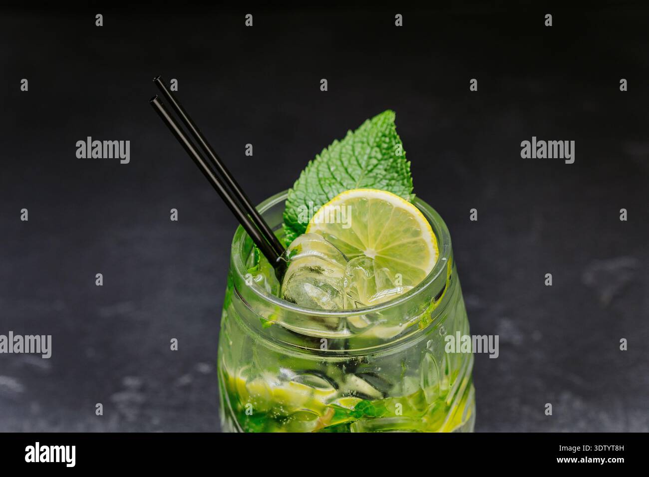 Cocktail de mojito frais avec citron vert, menthe et glace dans le verre sur fond sombre Banque D'Images