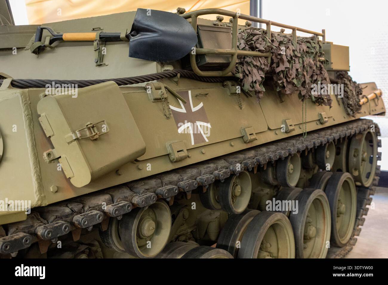 Vue latérale du char militaire blindé avec filet de camouflage et détail du système de piste Banque D'Images