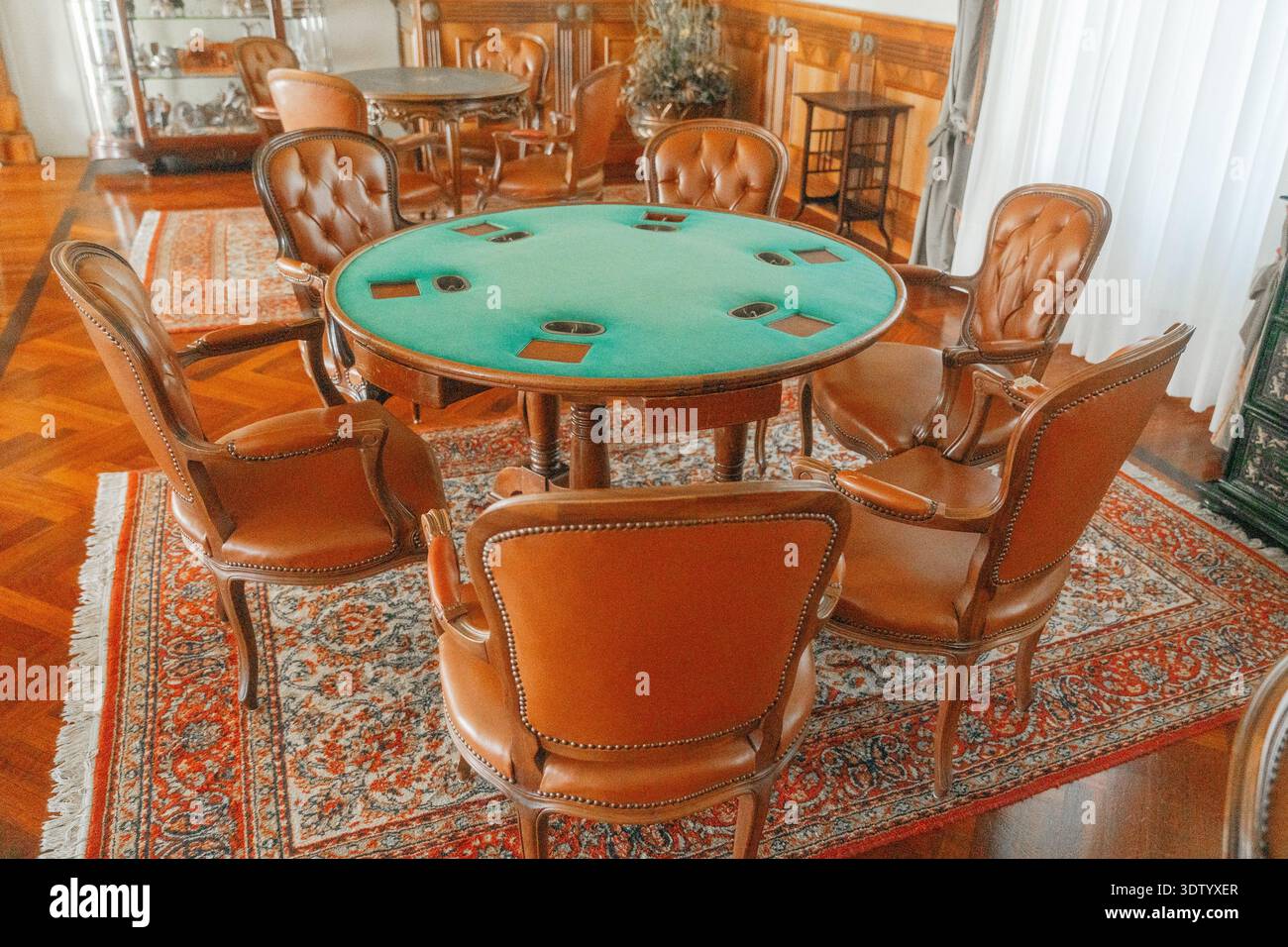 Table de jeu en feutre vert entourée de chaises en cuir à l'intérieur classique. Décor élégant en bois et ambiance vintage. Banque D'Images