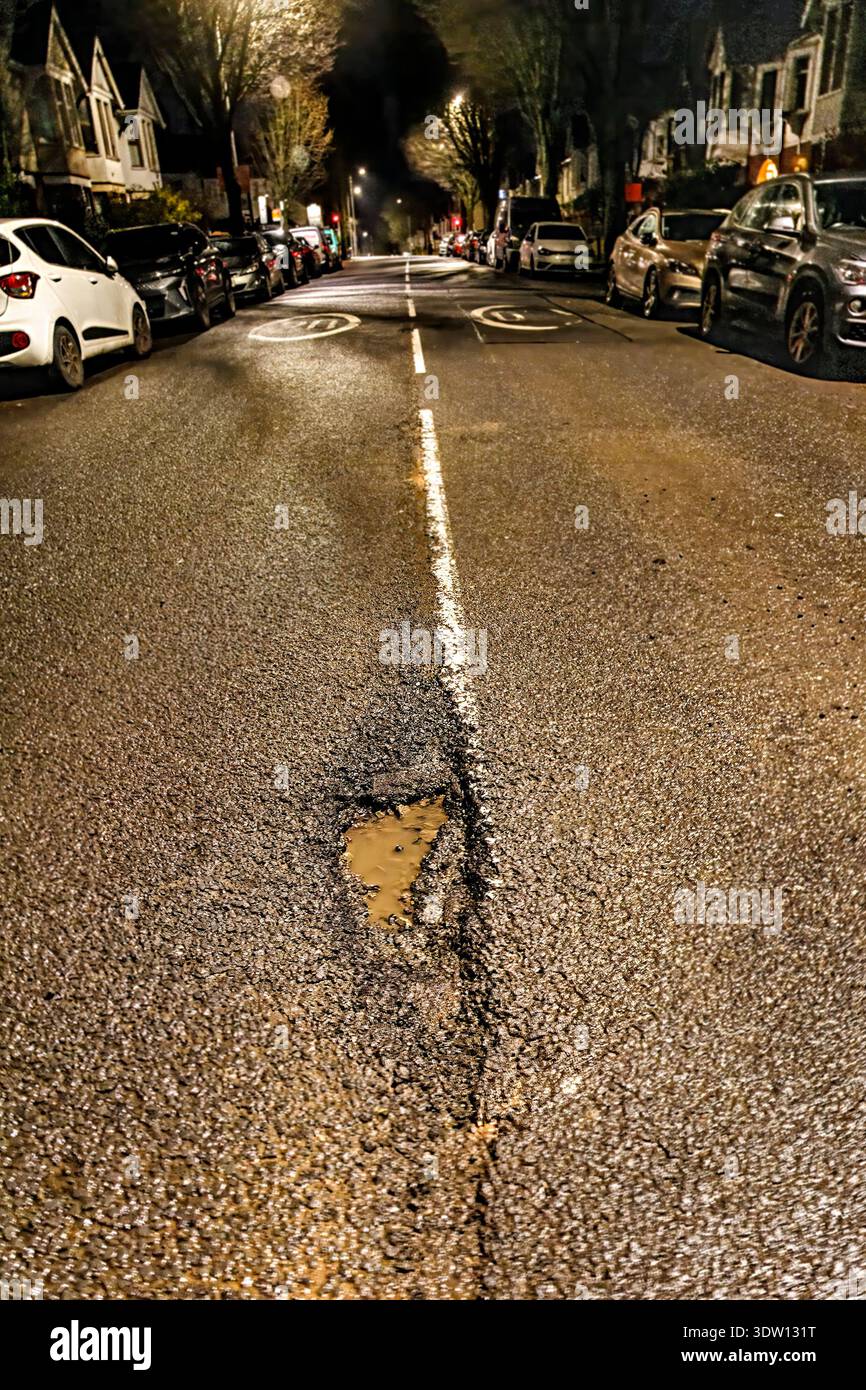 Nid de poule sur la route la nuit, un danger pour la sécurité, Cardiff, pays de Galles, Royaume-Uni Banque D'Images