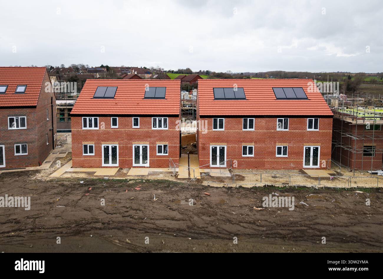 Vue aérienne au-dessus des maisons neuves semi-détachées abordables avec des systèmes de chauffage respectueux de l'environnement, y compris des panneaux solaires sur le toit sur un chantier de construction dans le Banque D'Images