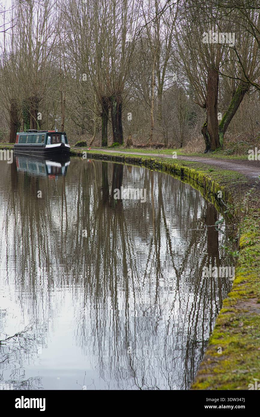 Bateau étroit amarré le long du chemin de fer bordé d'arbres du canal Peak Forest, Tameside, Royaume-Uni. Banque D'Images