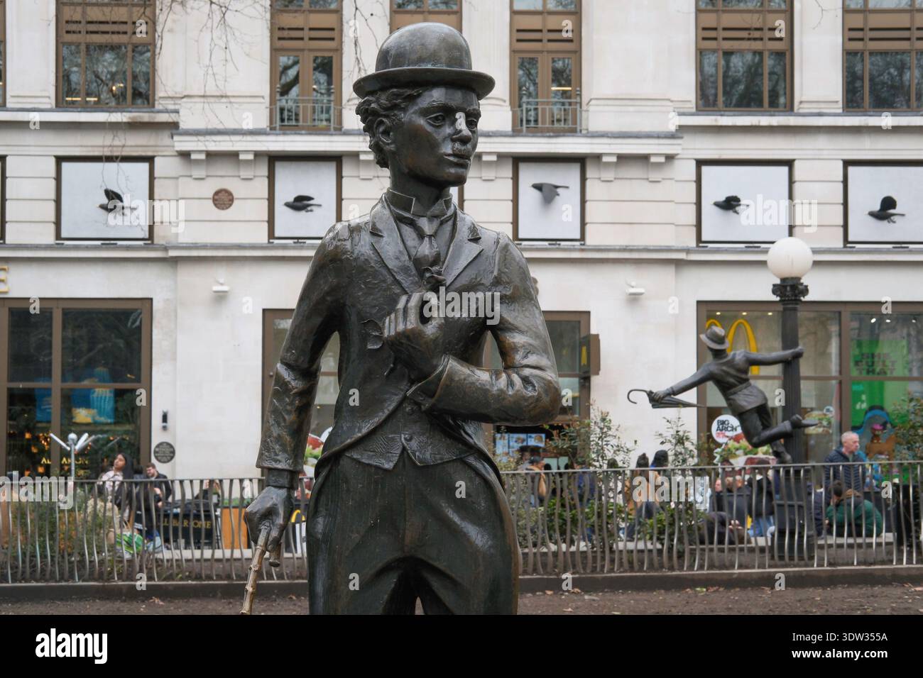 Statue de Charlie Chaplin dans le rôle de son personnage de Tramp, l'un des personnages de cinéma emblématiques célébré dans Scenes in the Square, Leicester Square, Londres, Royaume-Uni Banque D'Images