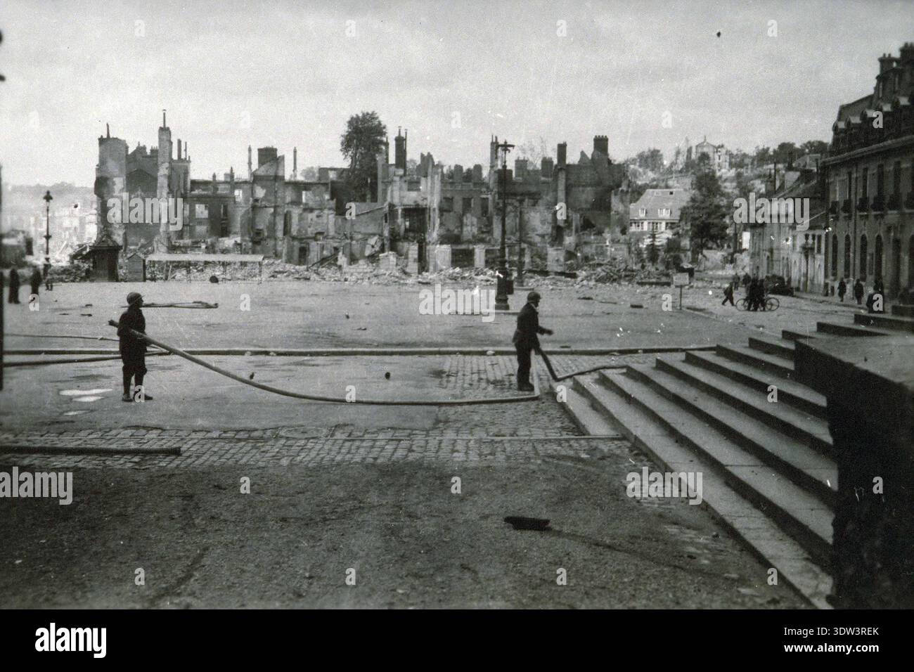 Civils dans la ville dévastée de Lisieux après le raid aérien allié du 6 juin 1944. Le 6 juin 1944, une énorme force d'invasion Alllied impliquant 7000 navires et 140 000 hommes débarque avec succès sur les côtes françaises et établit cinq têtes de plage. Une campagne de tromperie réussie signifiait qu'une grande partie de la résistance allemande était à Calais et que les pertes étaient relativement peu nombreuses compte tenu de l'ampleur et des dangers de l'opération. De nombreuses villes françaises historiques ont été détruites avant et pendant les débarquements. Banque D'Images
