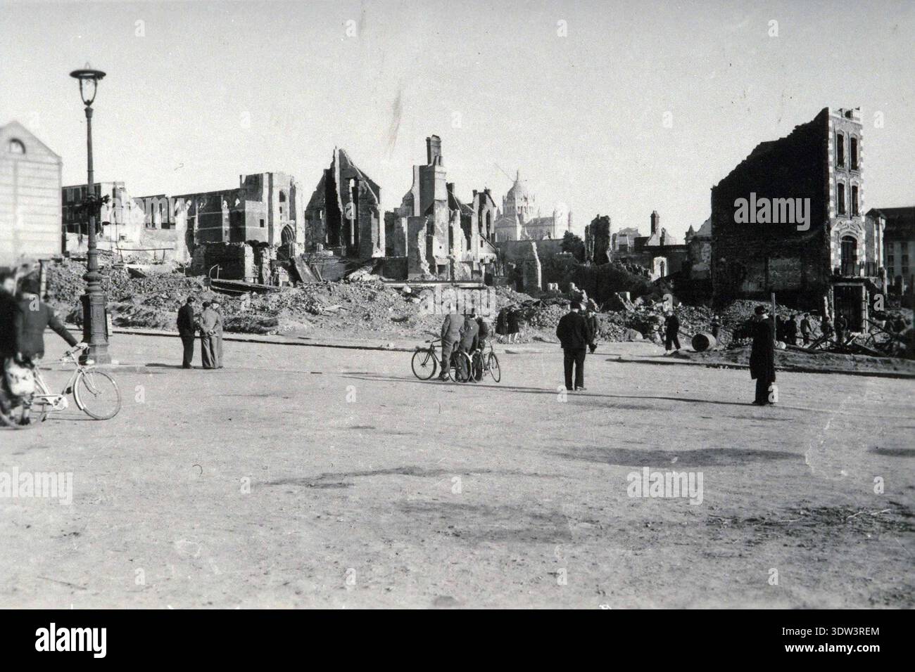 Civils dans la ville dévastée de Lisieux après le raid aérien allié du 6 juin 1944. Le 6 juin 1944, une énorme force d'invasion Alllied impliquant 7000 navires et 140 000 hommes débarque avec succès sur les côtes françaises et établit cinq têtes de plage. Une campagne de tromperie réussie signifiait qu'une grande partie de la résistance allemande était à Calais et que les pertes étaient relativement peu nombreuses compte tenu de l'ampleur et des dangers de l'opération. De nombreuses villes françaises historiques ont été détruites avant et pendant les débarquements. Banque D'Images
