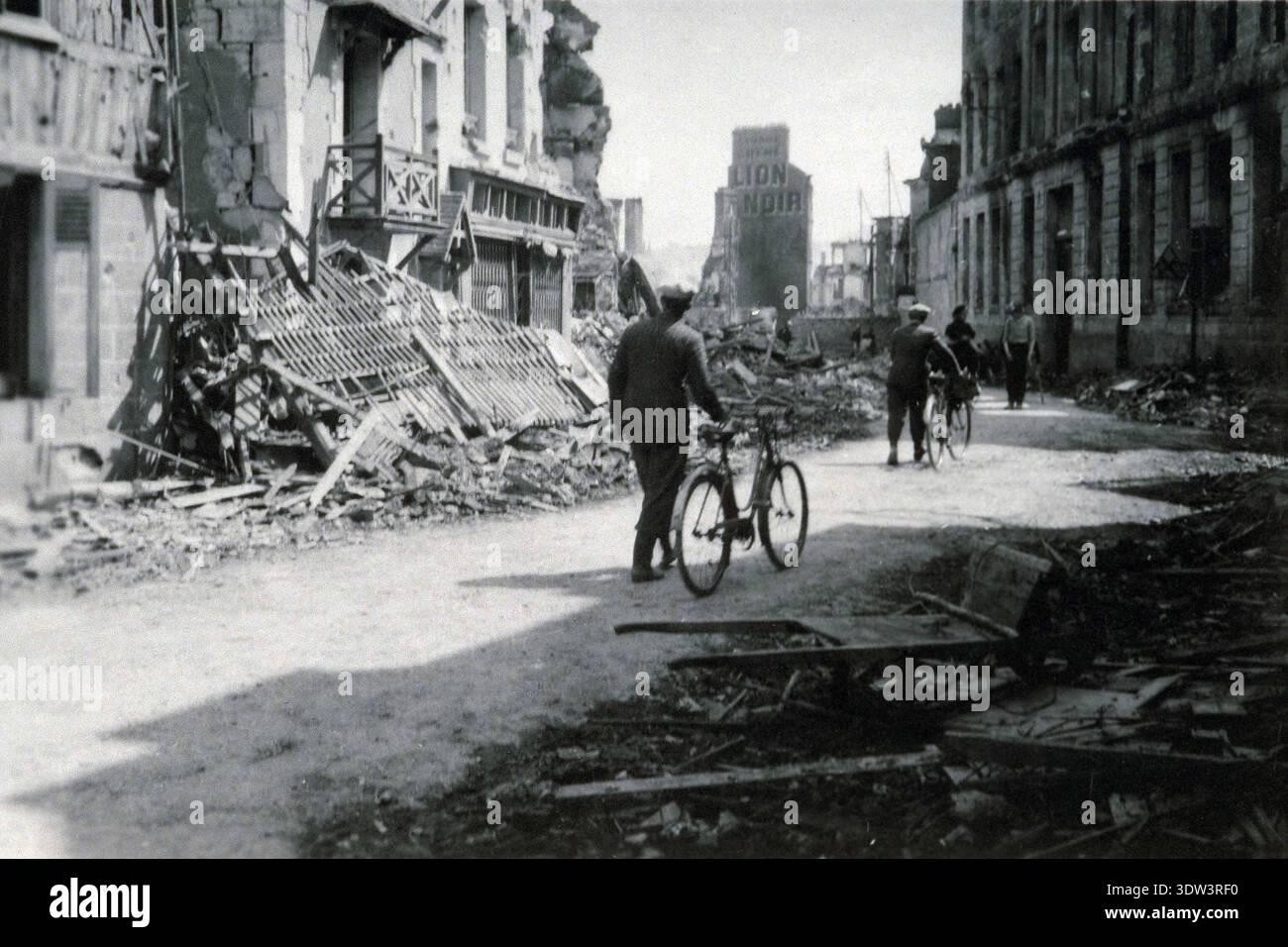 Civils dans la ville dévastée de Lisieux après le raid aérien allié du 6 juin 1944. n le 6 juin 1944, une énorme force d'invasion Alllied impliquant 7000 navires et 140 000 hommes débarque avec succès sur les côtes françaises et établit cinq têtes de plage. Une campagne de tromperie réussie signifiait qu'une grande partie de la résistance allemande était à Calais et que les pertes étaient relativement peu nombreuses compte tenu de l'ampleur et des dangers de l'opération. De nombreuses villes françaises historiques ont été détruites avant et pendant les débarquements. Banque D'Images