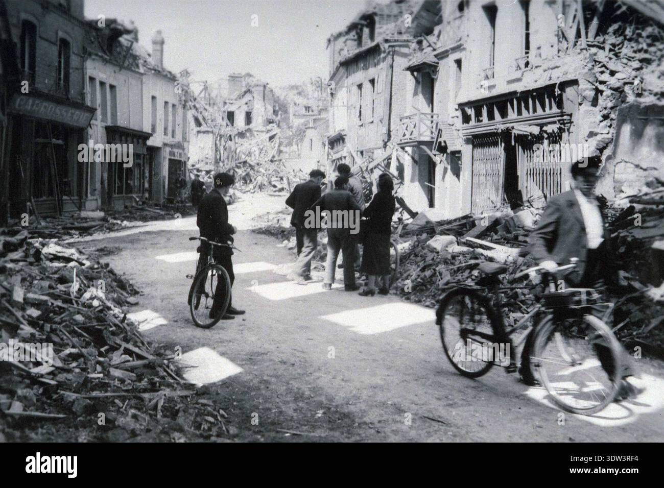 Civils dans la ville dévastée de Lisieux après le raid aérien allié du 6 juin 1944. n le 6 juin 1944, une énorme force d'invasion Alllied impliquant 7000 navires et 140 000 hommes débarque avec succès sur les côtes françaises et établit cinq têtes de plage. Une campagne de tromperie réussie signifiait qu'une grande partie de la résistance allemande était à Calais et que les pertes étaient relativement peu nombreuses compte tenu de l'ampleur et des dangers de l'opération. De nombreuses villes françaises historiques ont été détruites avant et pendant les débarquements. Banque D'Images