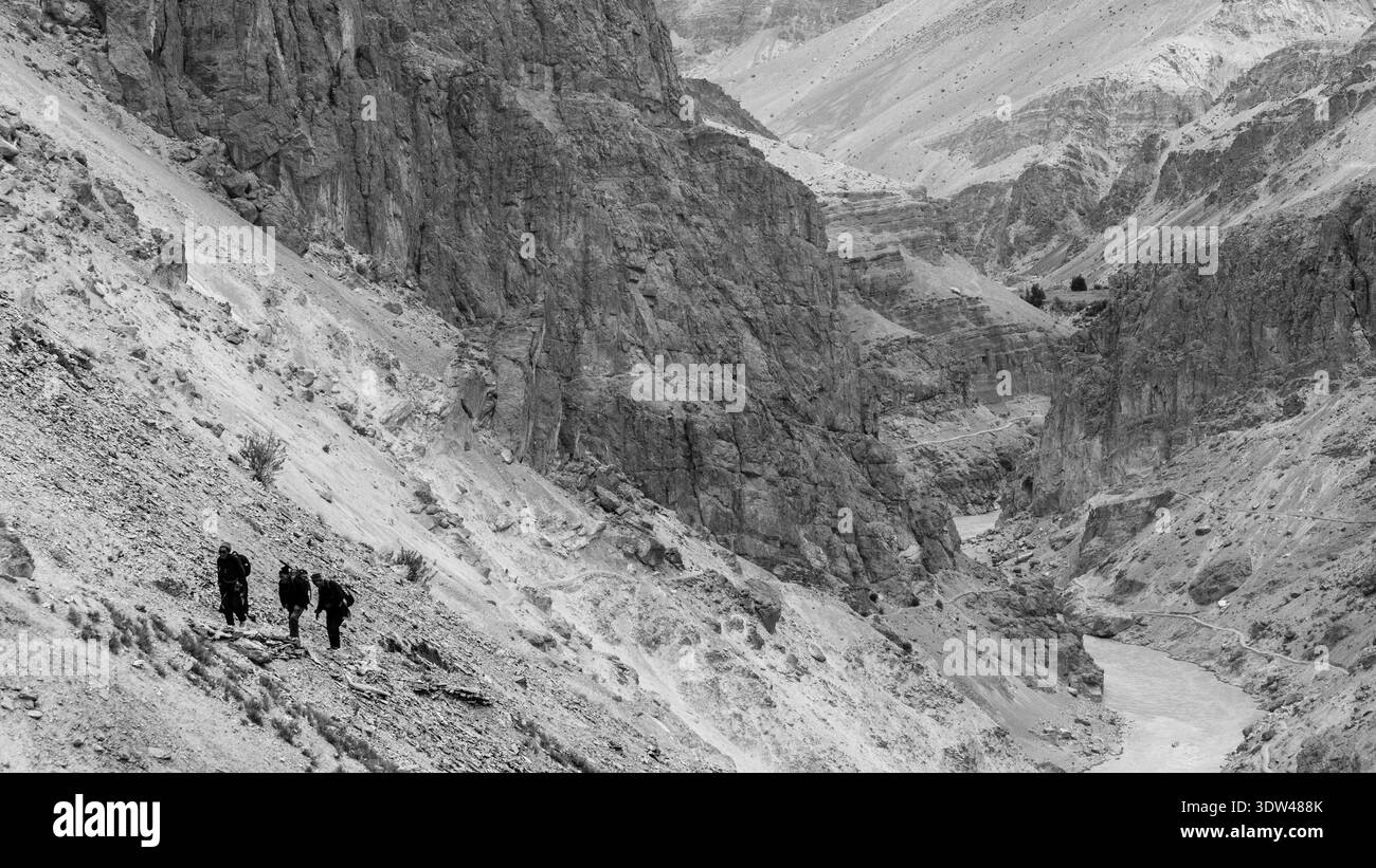 Trois randonneurs traversent un sentier de montagne accidenté. Banque D'Images