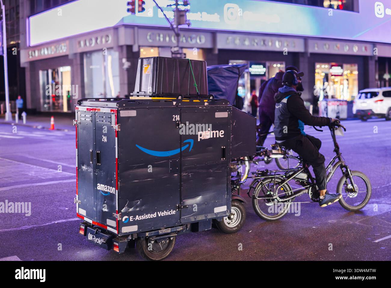 New-York, États-Unis, 1er novembre 2025 : livreur Amazon Prime chevauchant un vélo de fret électrique dans la rue de la ville la nuit avec des lumières urbaines Banque D'Images