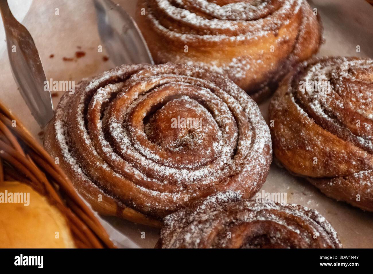 Gros plan d'un rouleau de cannelle fraîchement cuit avec des couches tourbillonnantes de pâte et de fourrage à la cannelle, mettant en valeur sa texture douce et sa croûte dorée Banque D'Images