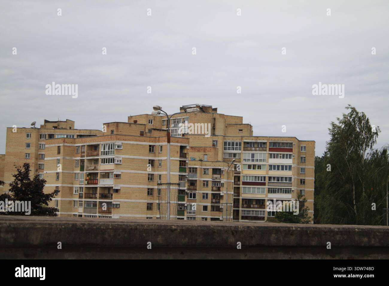 Grand immeuble d'appartements de l'ère soviétique avec plusieurs balcons et fenêtres résidentielles sous le ciel nuageux. Banque D'Images