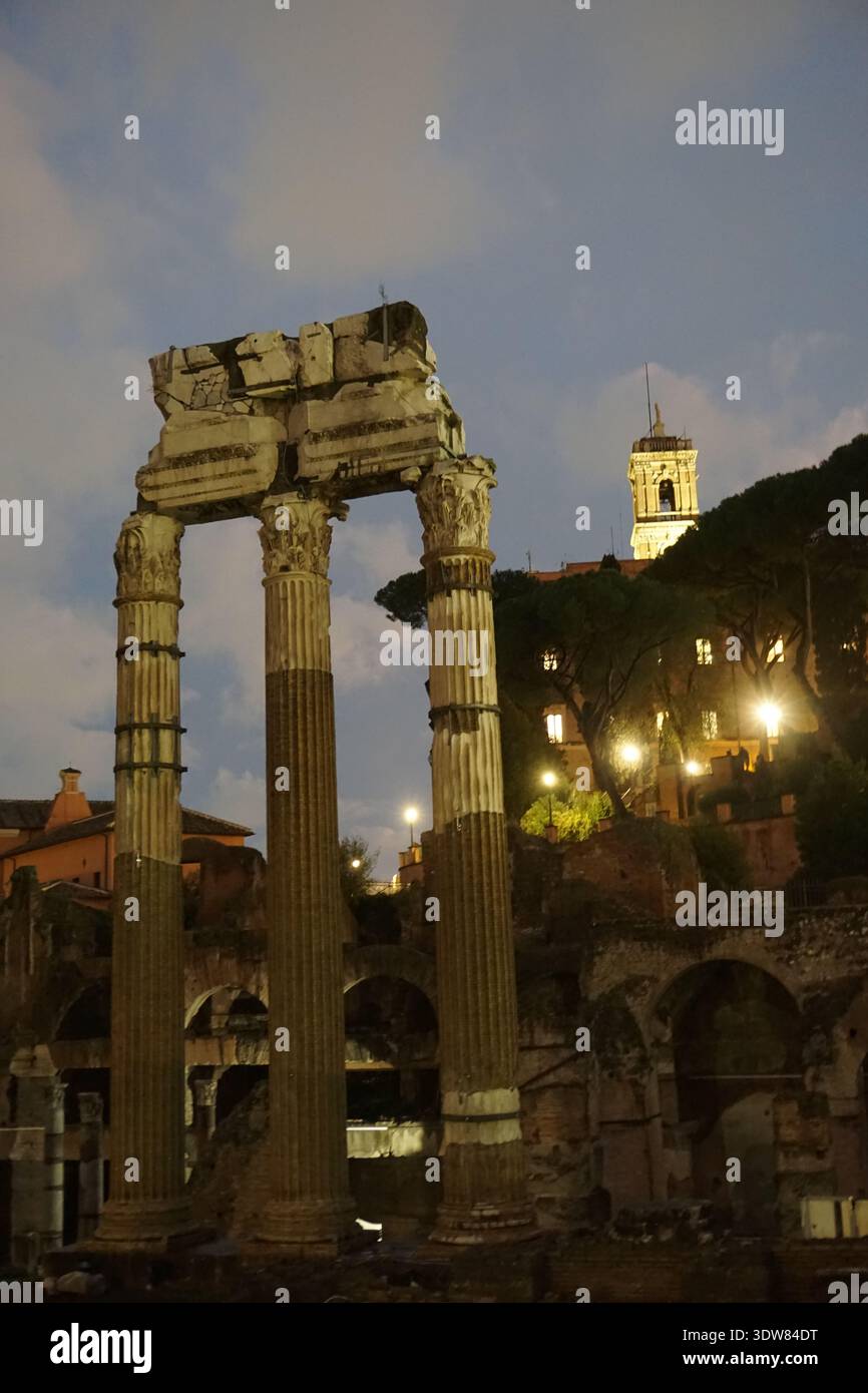 Les ruines d'une ancienne porte romaine avec des colonnes classiques se dressent au Forum Romanum à Rome, en Italie, la nuit. Banque D'Images