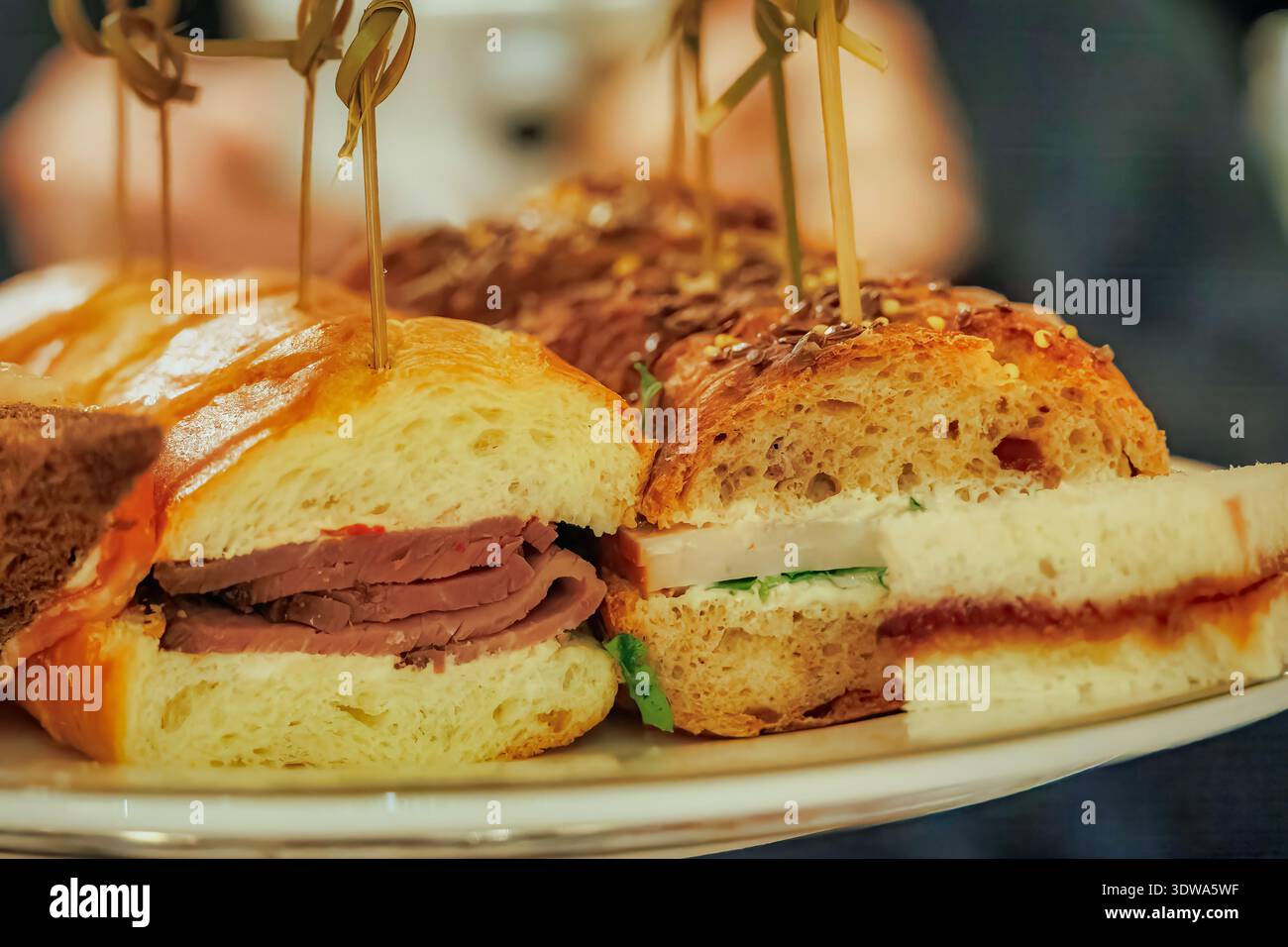 Assortiment de mini-sandwichs gastronomiques sur un plateau de service dans un cadre de restauration avec éclairage intérieur doux Banque D'Images