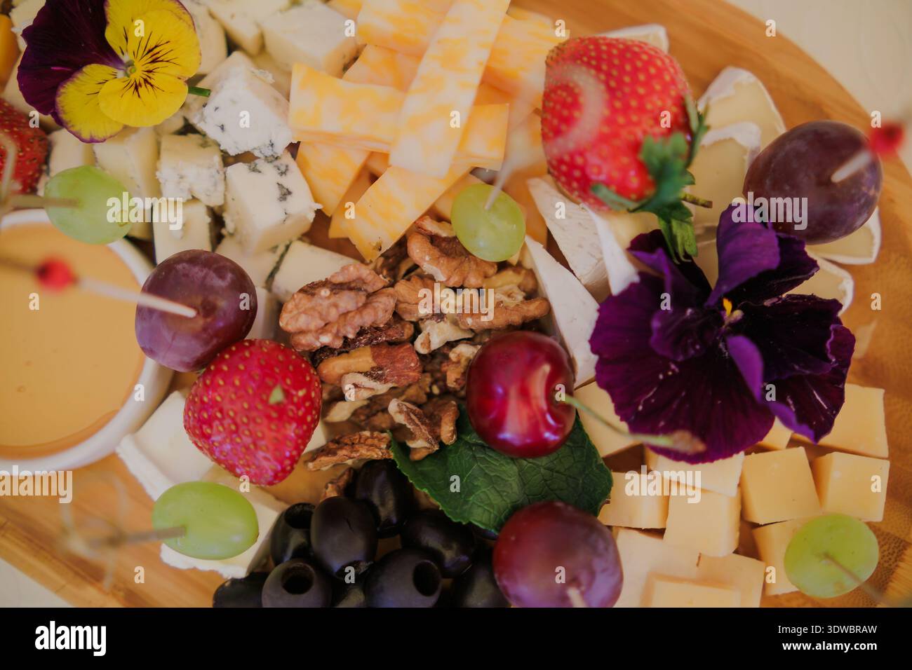 Une assiette avec assortiment de fromages, fruits, noix et miel Banque D'Images