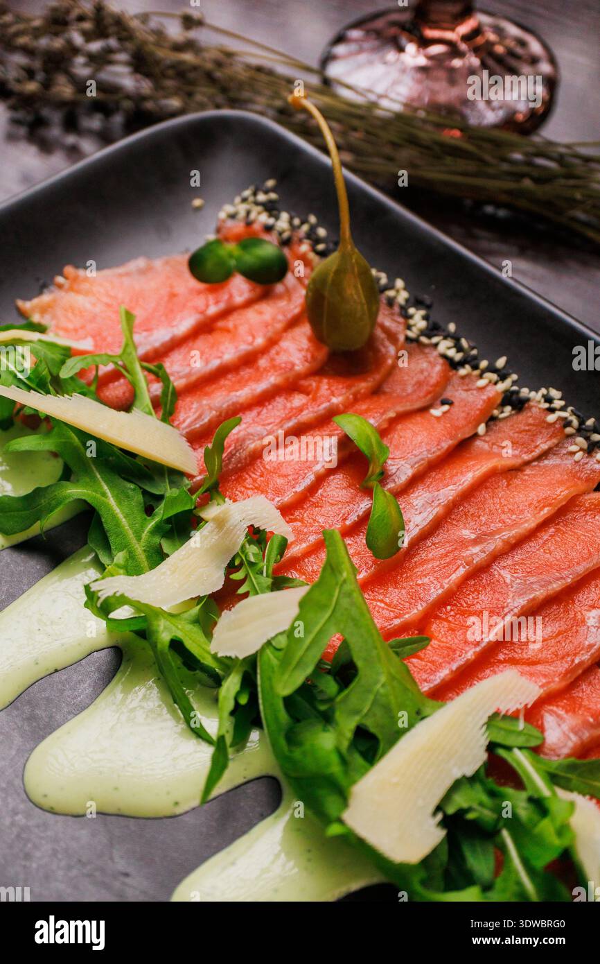 Une assiette avec des tranches de poisson rouge, du pain et des légumes verts Banque D'Images