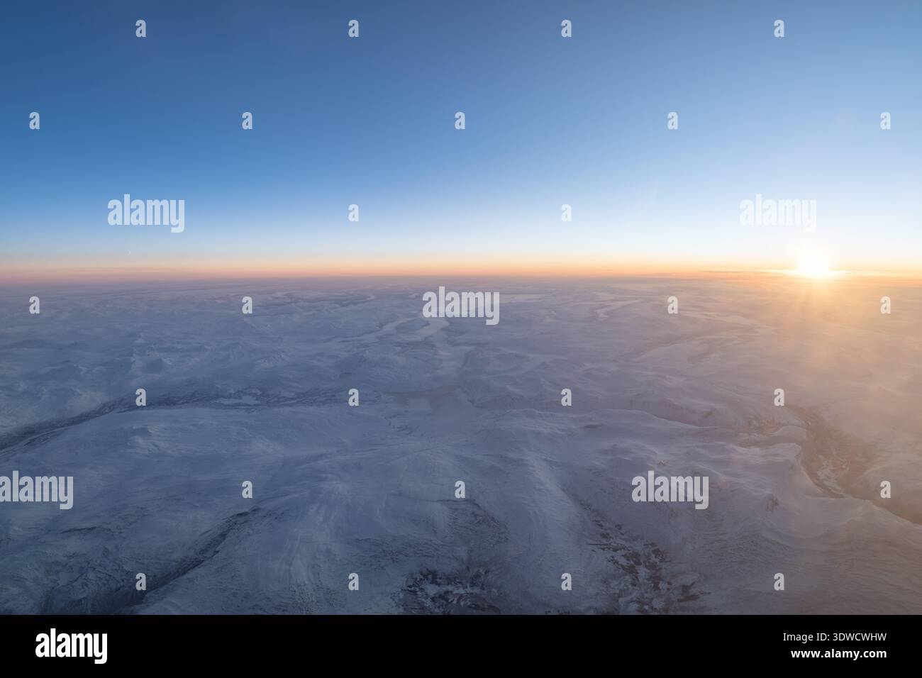 Vue aérienne mettant en valeur un vaste paysage arctique enneigé avec un soleil levant Banque D'Images