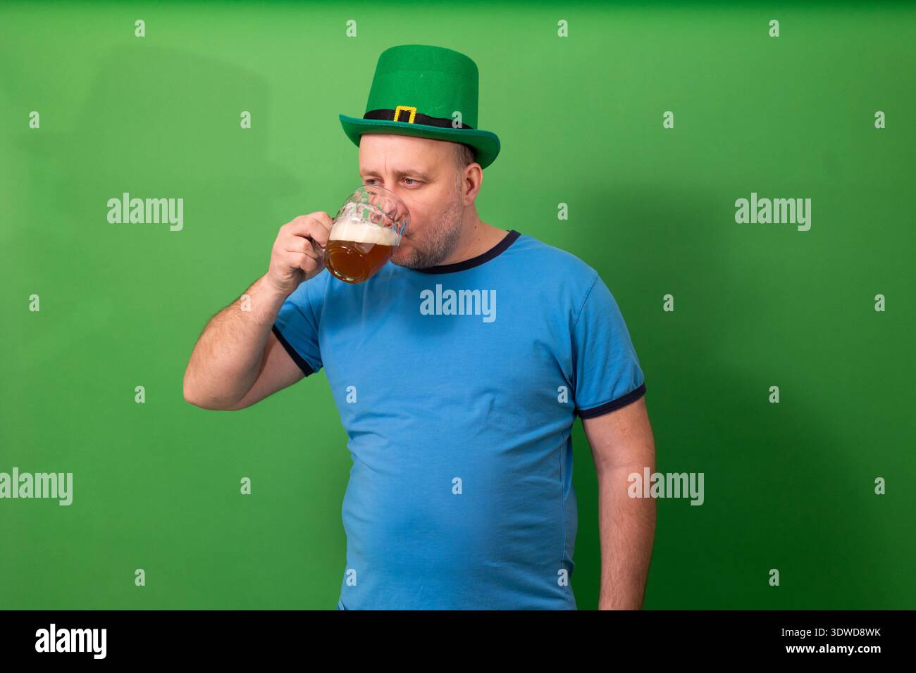 Homme buvant de la bière tout en portant un chapeau de leprechaun vert. – Toast festif de Patricks Day. Célébration des fêtes irlandaises et photographie de tradition pub Banque D'Images