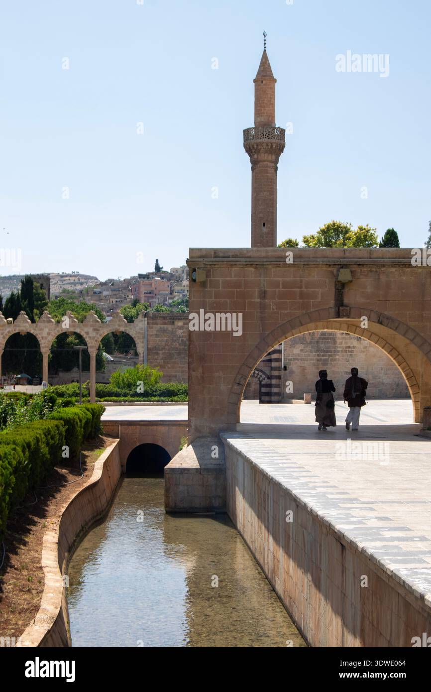 Une scène sereine au cœur de l'Anatolie mettant en valeur l'architecture historique, y compris un ancien minaret et une arche à côté d'une voie navigable tranquille. Banque D'Images
