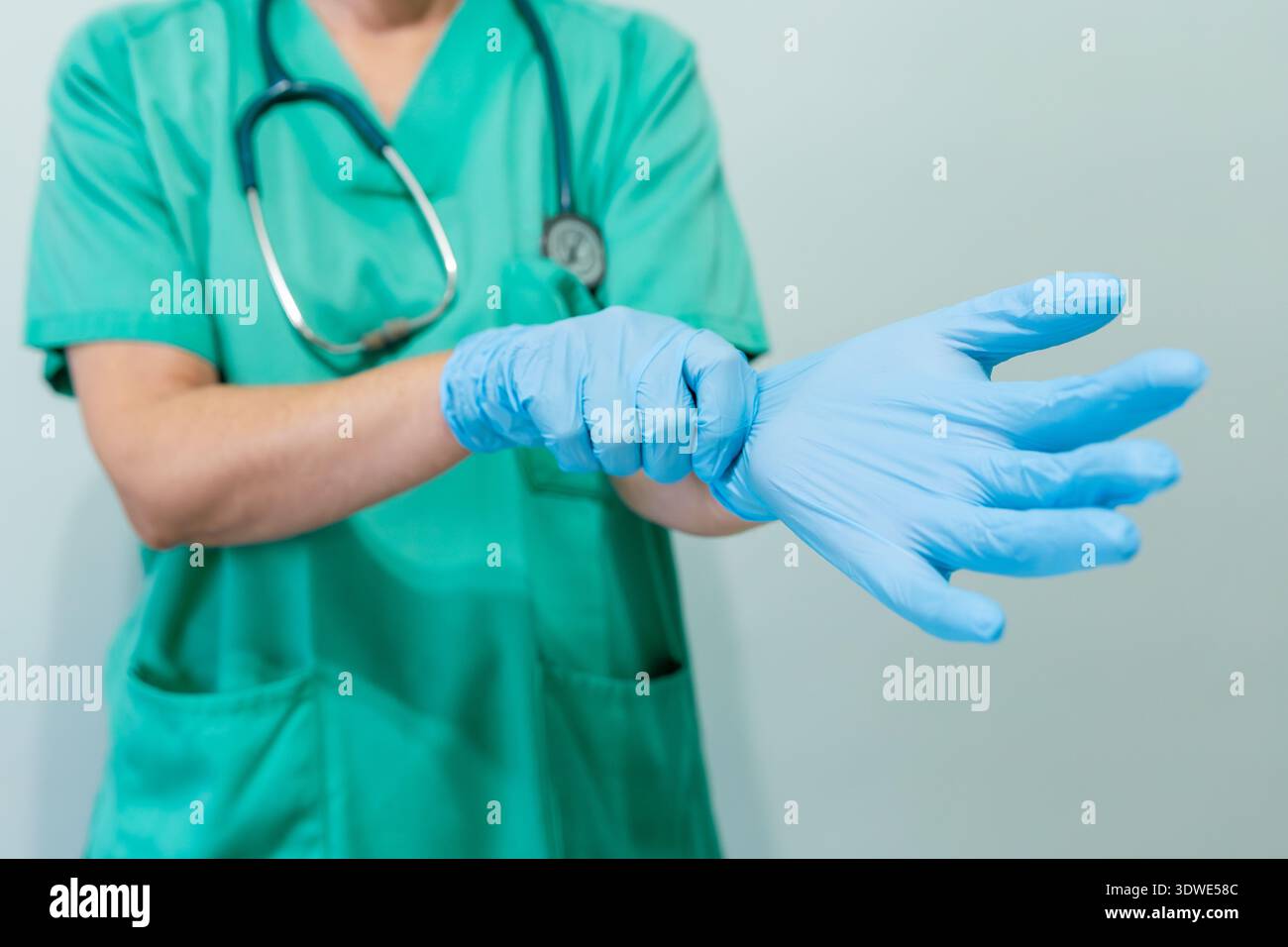 Image recadrée méconnaissable d'une professionnelle de la santé portant un uniforme médical vert et portant des gants de protection bleus. Concentrez-vous sur le a Banque D'Images