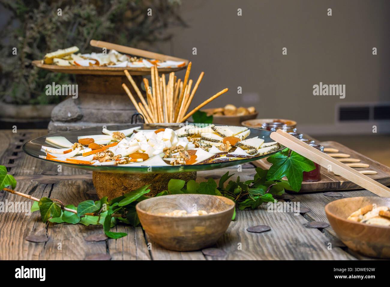 Un plat magnifiquement agencé avec une sélection de fromages assortis, accompagnés de gressins et de noix croquants. Parfait pour les amateurs de gastronomie Banque D'Images