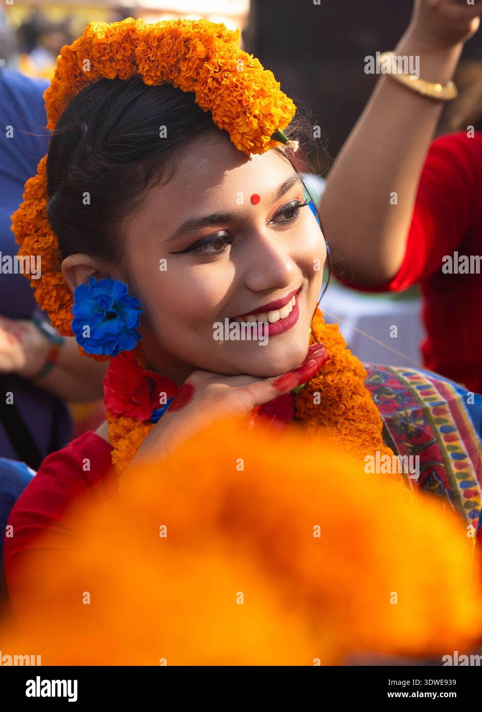Dhaka, Bangladesh - 04 mars 2018 : vue d'une jeune femme ornée de soucis oranges vibrants et d'une fleur bleue saisissante, son visage rayonnant de joie Banque D'Images