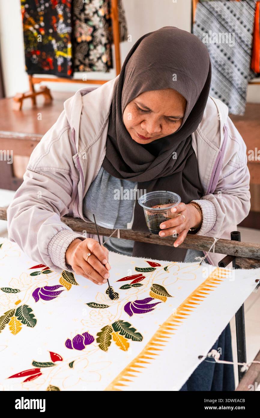 Un artisan indonésien peint habilement à la main un design batik, mettant en valeur ce patrimoine culturel immatériel reconnu par l'UNESCO avec des motifs vibrants et Banque D'Images