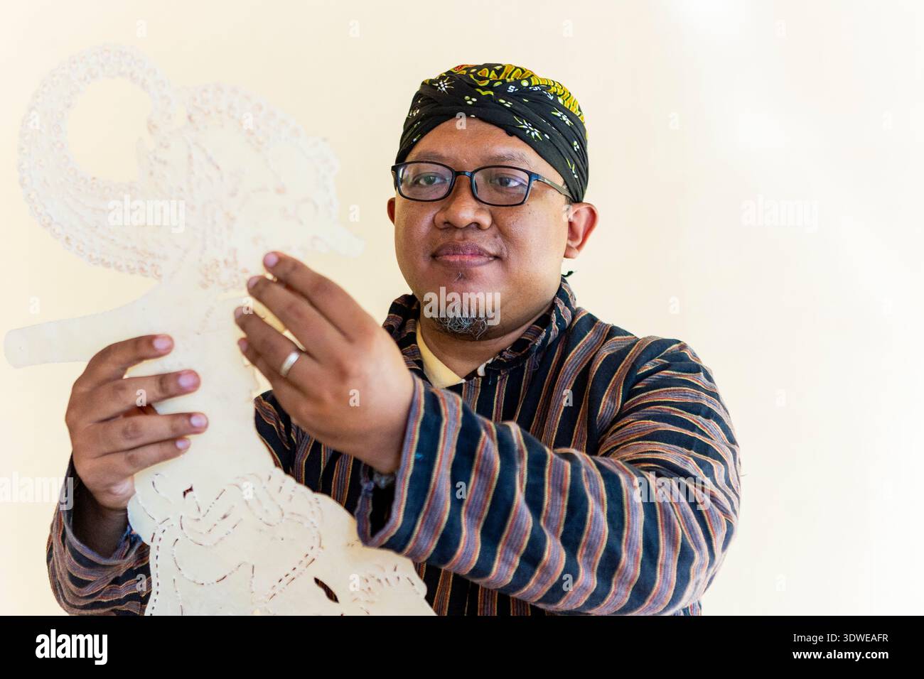 Un artisan javanais qualifié présentant le wayang kulit fait main complexe, une marionnette d'ombre traditionnelle, mettant en valeur le riche patrimoine et culturel Ar Banque D'Images